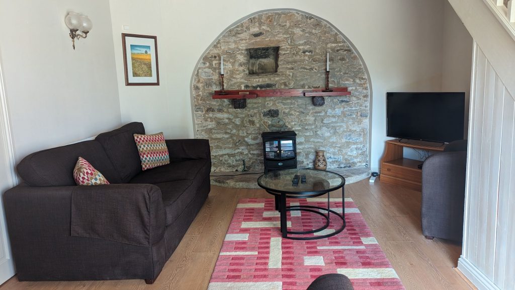 Picture of Barn Cottage Living Room, with a 3 seater sofa, TV, electric fire and glass/metal coffee tables